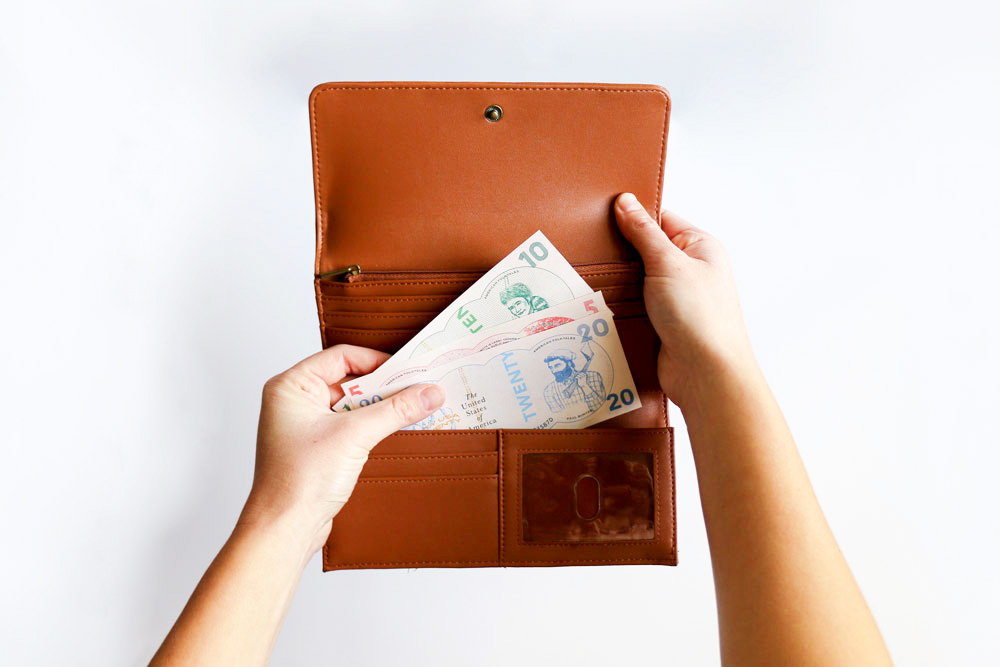 Image of hands holding a billfold and pulling out colorful dollar bills